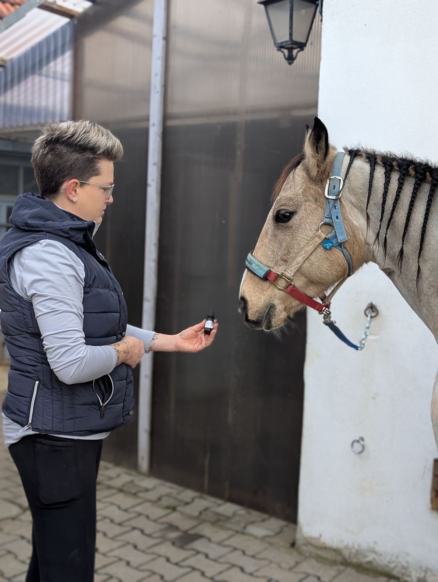 Sabrina hält einem Pferd ein Fläschchen ätherisches Öl zum Schnuppern hin